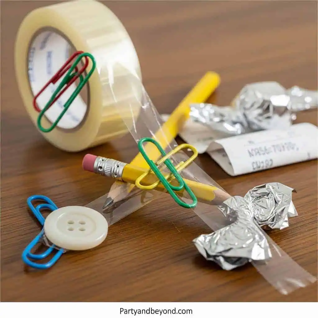 Creative Minute to Win It game setup with paper clips, tape, and candies.