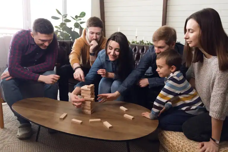 Group of adults and a child playing Jenga at a cozy indoor gathering.