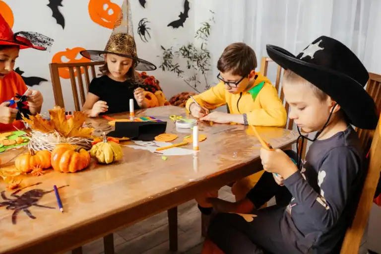 Kids making Halloween crafts at a themed party with pumpkins and decorations.