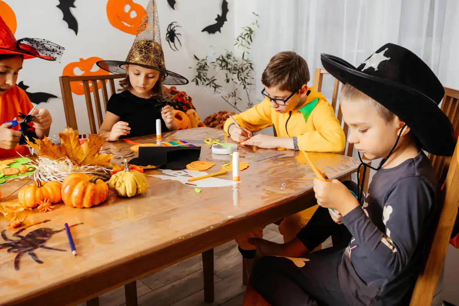 Kids making Halloween crafts at a themed party with pumpkins and decorations.
