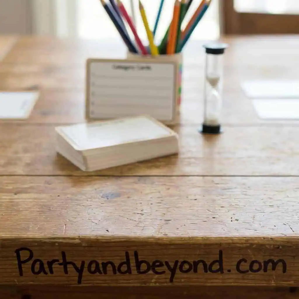 Table with colorful pens, notepad, and hourglass for dinner party games.