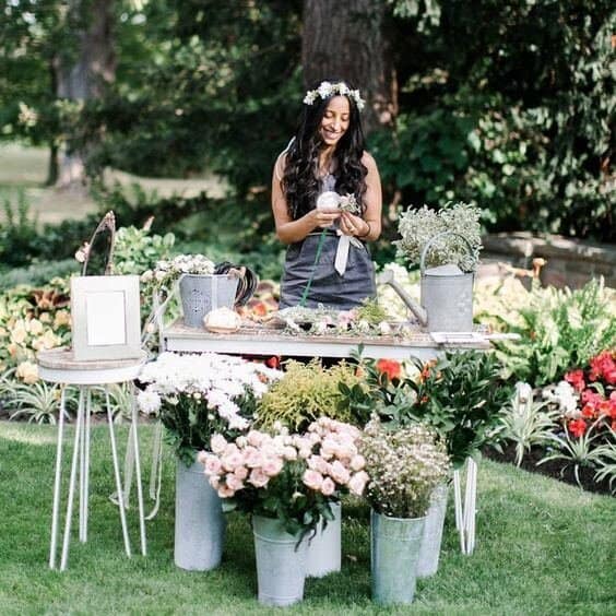 Flower crown station with a woman arranging flowers at a wedding