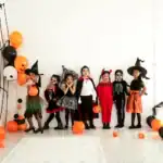 29 Spooky Halloween Backdrop Ideas for Your Next Party Kids dressed in Halloween costumes with pumpkins and decorations for spooky party.