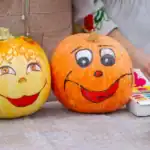 39 Elegant Pumpkin Painting Ideas for a Chic Fall Décor Two decorated pumpkins with cheerful faces for fall and Halloween decor.