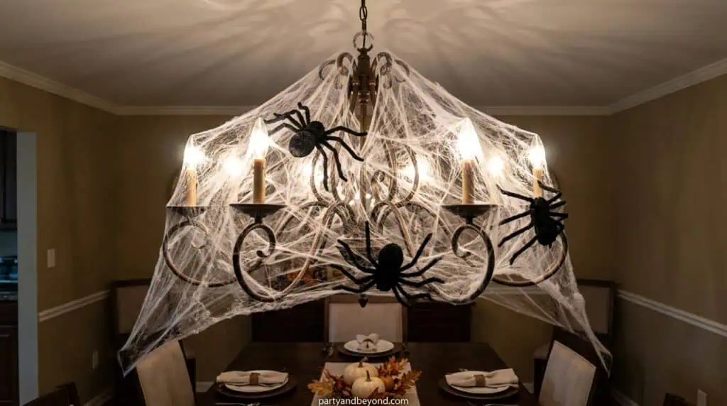 Chandelier wrapped in cobwebs with hanging spiders creating eerie dining room lighting