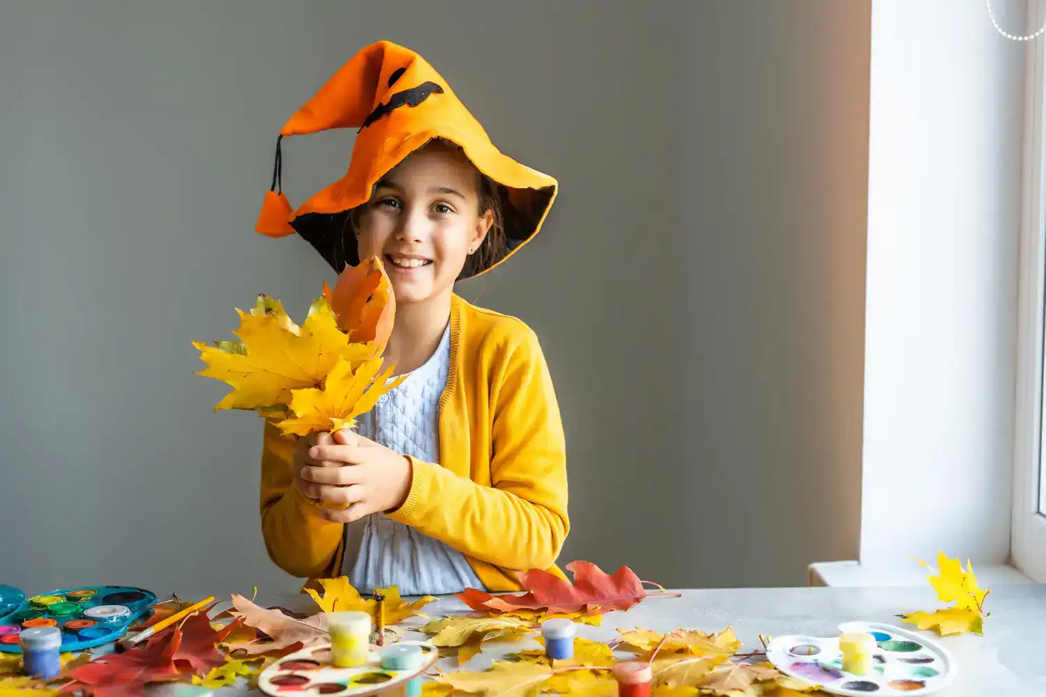 Happy girl in fall costume with leaves, celebrating autumn crafts for kids.