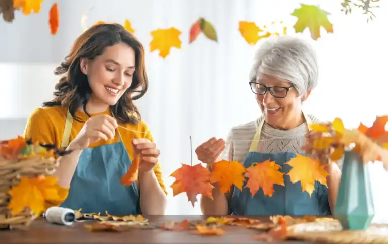 Autumn craft activity with two women creating fall leaf decorations for seasonal home decor.