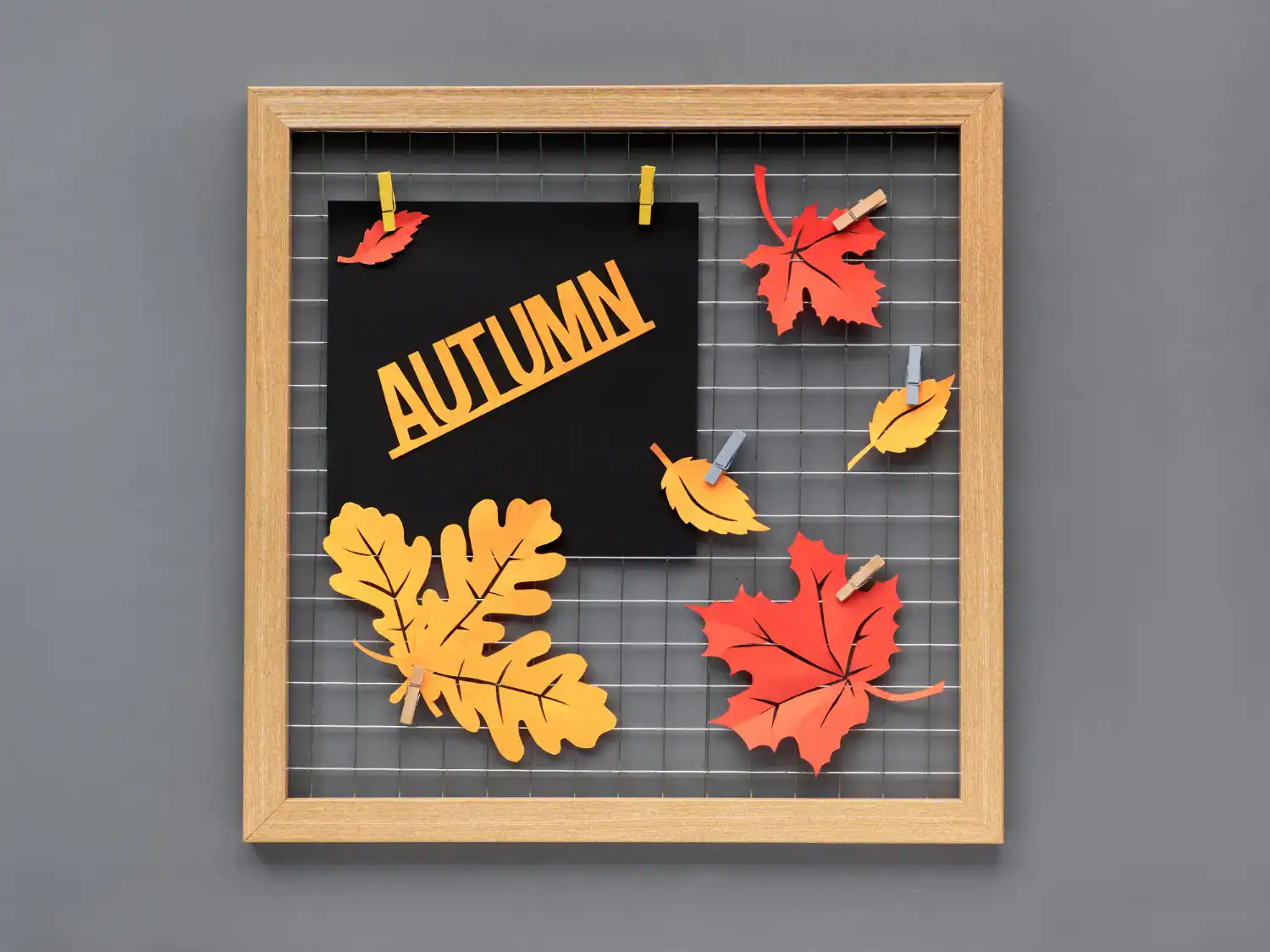 Fall leaf craft display with paper leaves on a wire grid for autumn decoration.