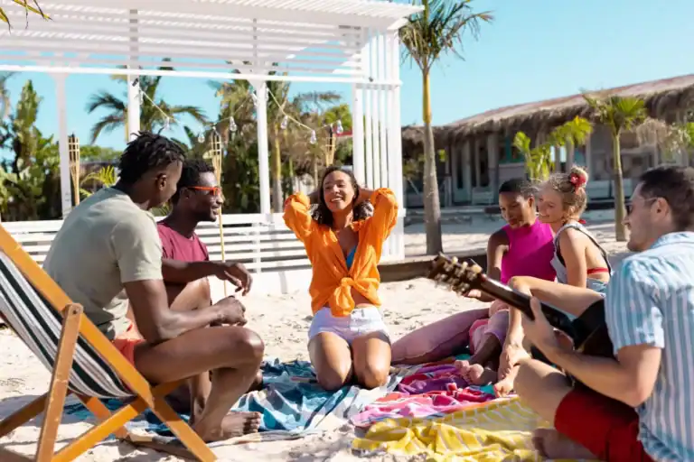 Group of friends enjoying luau party games on the beach.