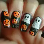 31 Creepy-Cool Halloween Nail Ideas to Rock This October Spooky Halloween nail design featuring ghosts and pumpkins on black background.