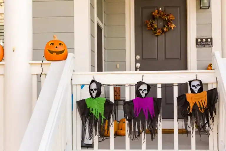 Pumpkin with carved face and hanging skeleton masks for Halloween decor.