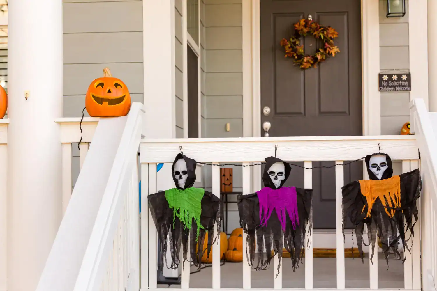 Pumpkin with carved face and hanging skeleton masks for Halloween decor.
