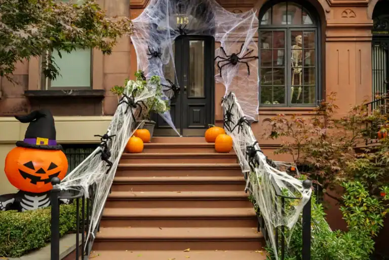 Scary Halloween outdoor decoration with cobwebs, spiders, pumpkins, and spooky accents on a brownsto.