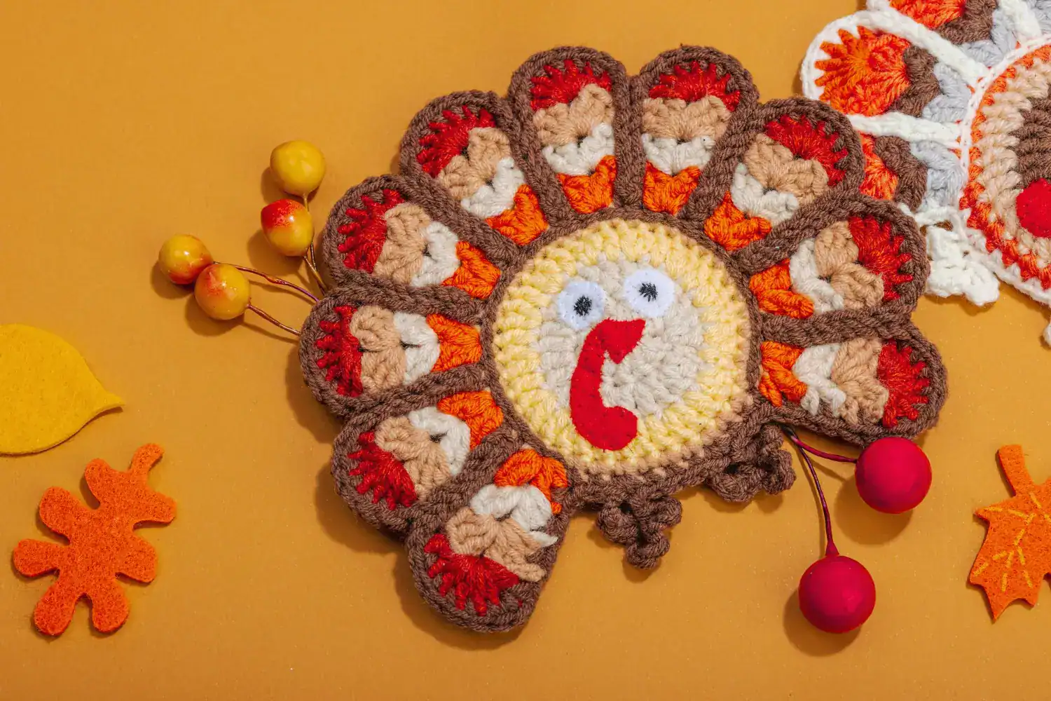 Colorful crochet turkey decoration with felt details and pom-pom accents.