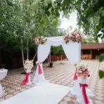 15 Stunning Wedding Reception Entrance Ideas for Bridal Party Outdoor wedding entrance with floral arrangements and white drapery.