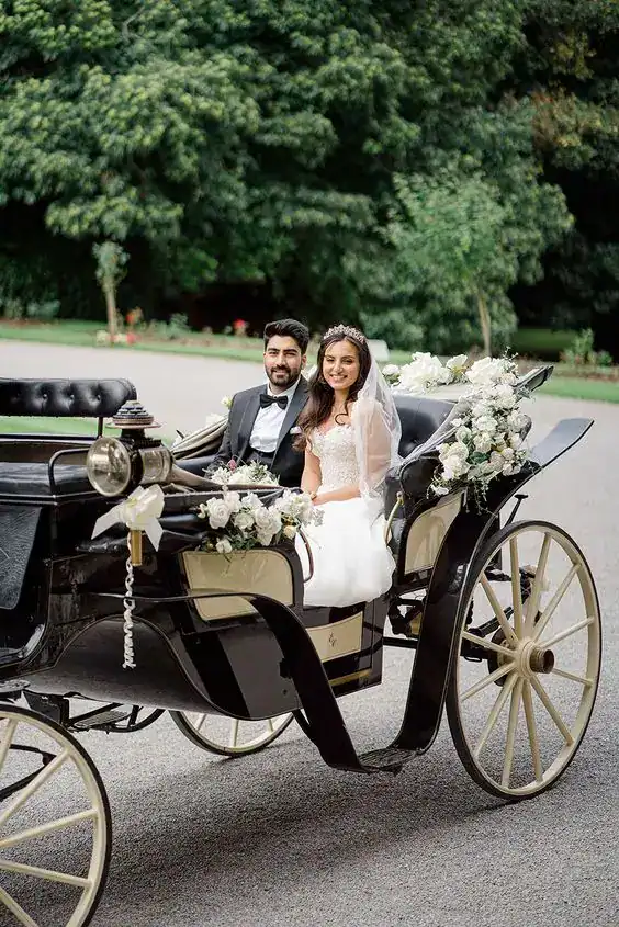 Vintage wedding carriage with bride and groom for wedding reception entrance.