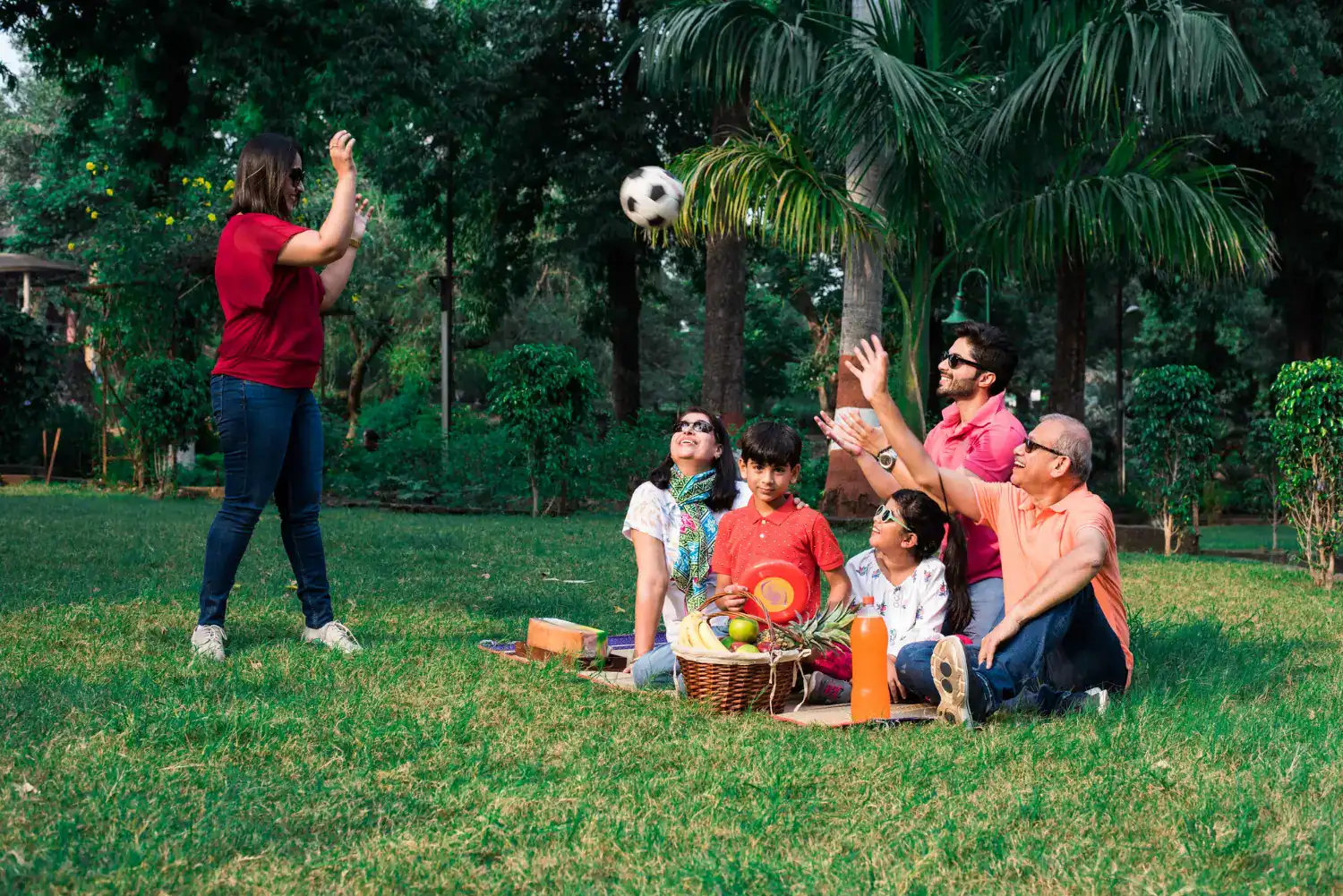 Family outdoor game with kids and adults playing with a soccer ball in a park.