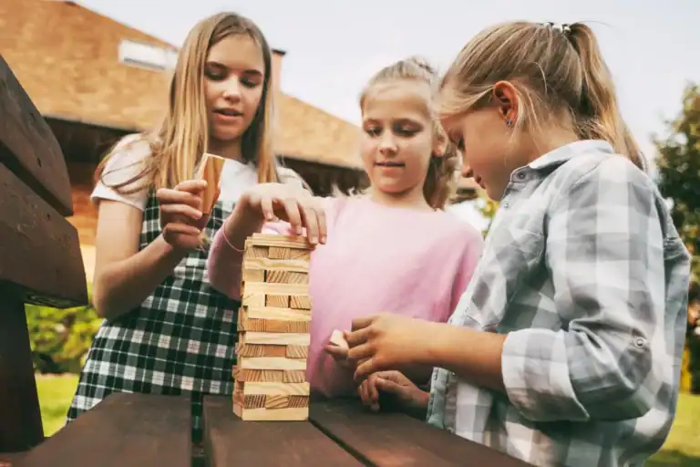 Children playing Jenga game outdoors at a kids' party.