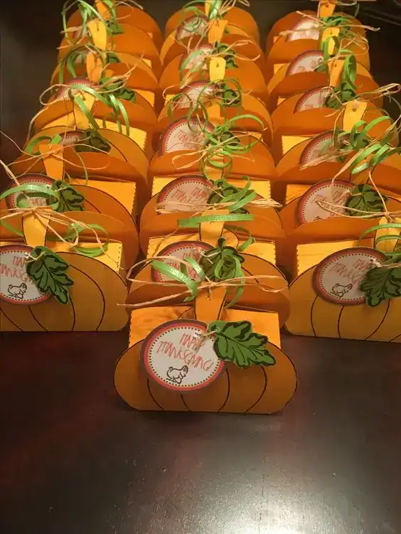 Festive pumpkin-shaped party favors with "Happy Thanksgiving" tags and green leaf decorations.