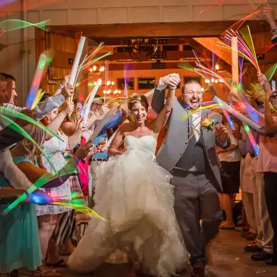 Joyful newlyweds entering wedding reception with confetti and guests celebrating.