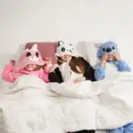 25 Sleepover Party Games for Teens That Are Guaranteed Fun Kids in animal-themed sleepover masks having fun in bed.