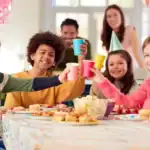 22 Teen Boy Birthday Party Ideas That Are Anything But Boring Happy teens celebrating birthday with party hats and snacks.