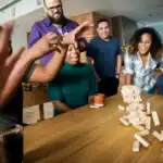 31 Hilarious TikTok Party Games and Challenges Everyone Will Love Group of friends playing Jenga at a lively party.