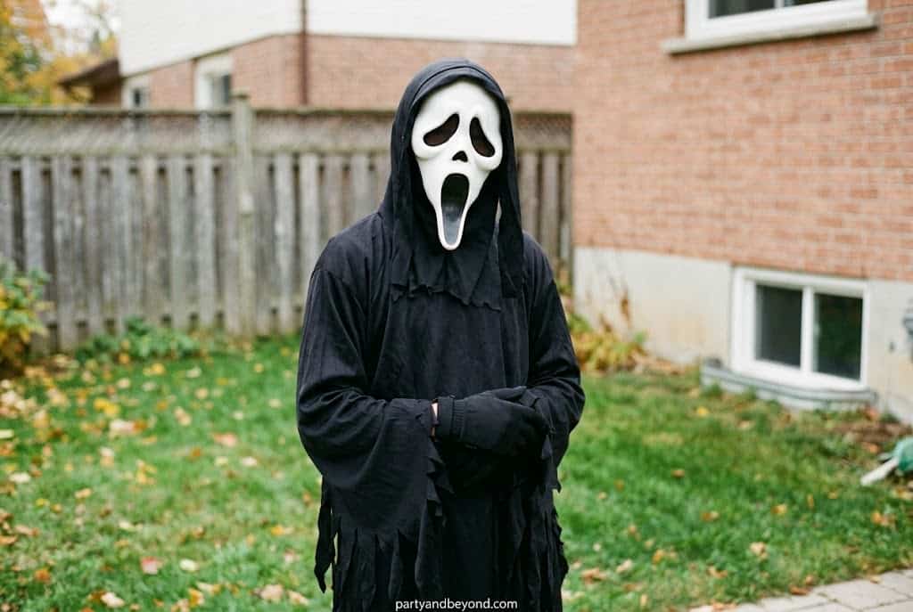 Teen boy wearing scary Ghostface Halloween costume with black robe and mask