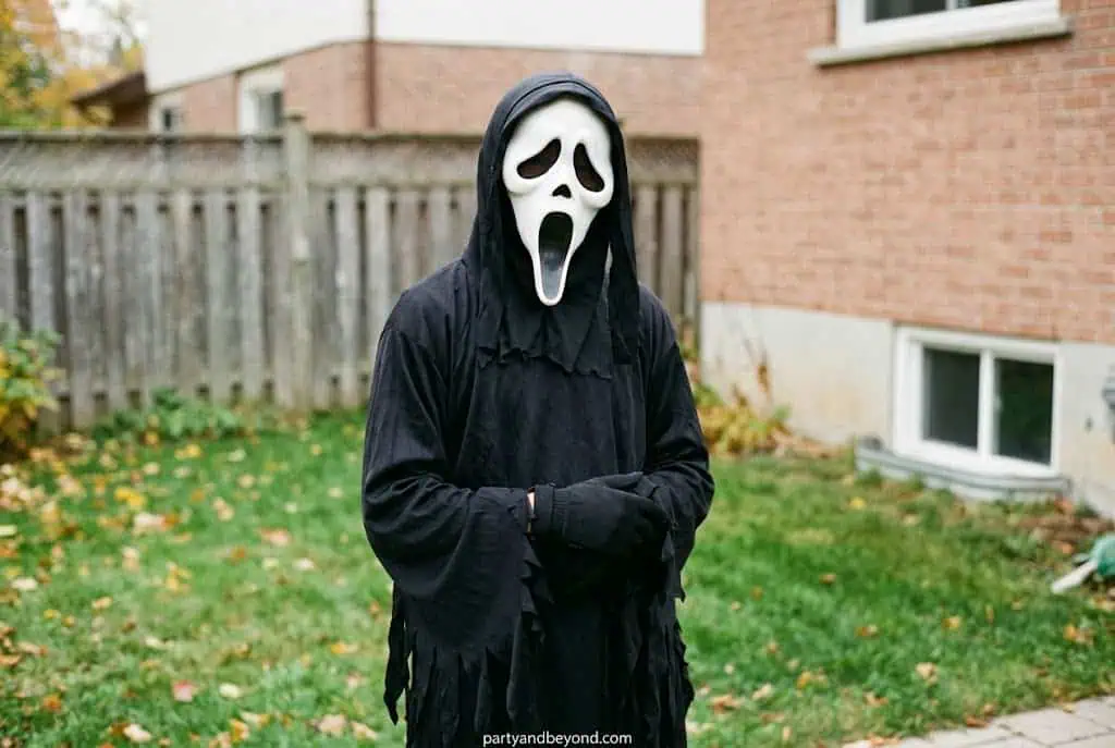 Teen boy wearing scary Ghostface Halloween costume with black robe and mask