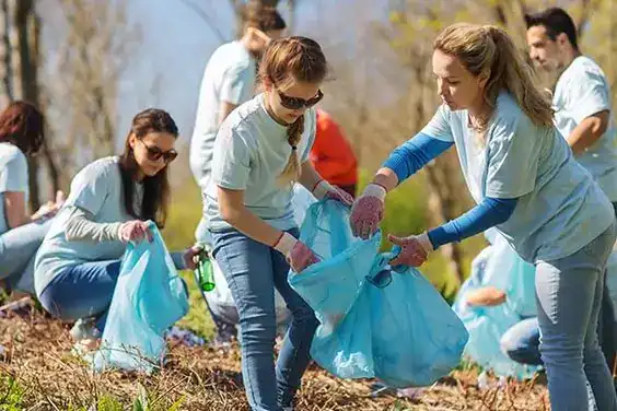 Teen volunteers collecting trash outdoors for a charity or environmental cause.