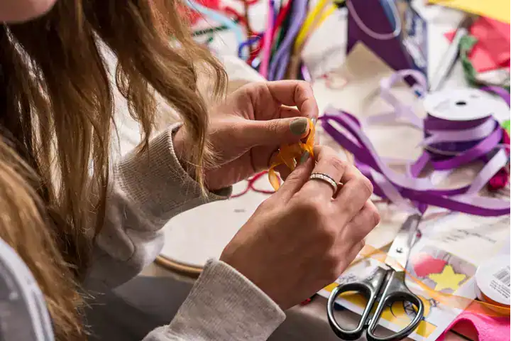 Teen crafting activity with ribbons and scissors for fundraising events.