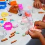 23 Sensory Party Games That Engage All 5 Senses (2026 Guide) Children engaging in sensory play with clay and textured materials for sensory development.