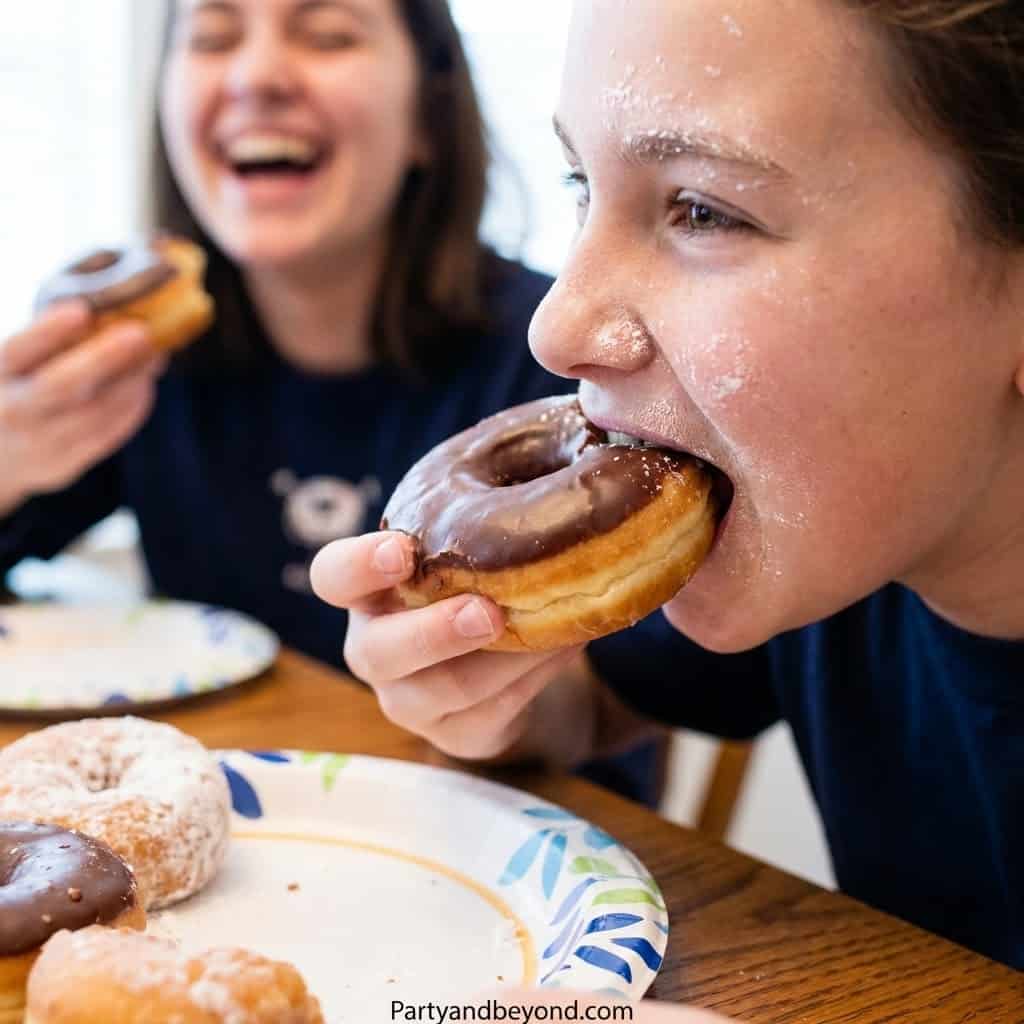 Teenagers enjoying donuts at a fun party game.