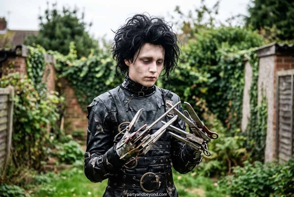 Teen dressed as Edward Scissorhands with silver scissor hands and messy hair