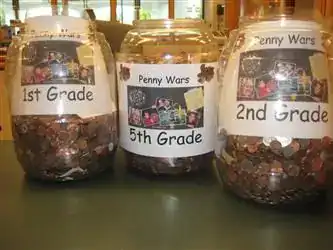 Penny Wars jars labeled for 1st, 2nd, and 5th grade to encourage fundraising among students.