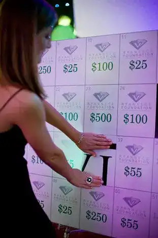 Girl playing fundraising game with prize board at event.