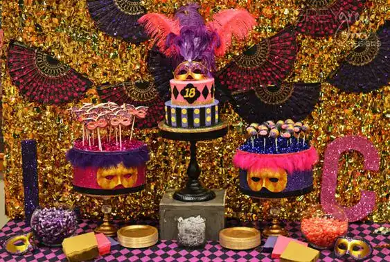 Elegant masquerade birthday party cake display with vibrant masks and feathers.