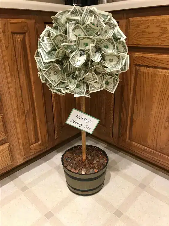 DIY money tree made with a small potted plant and dollar bills clipped to the branches