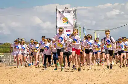 Group of teens running on the beach during a fundraising event.