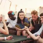 19 cool Teen-Favorite Party Games for Teenagers to Make the Night Epic Teenagers playing fun party card game outdoors.