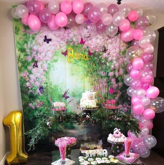 Beautiful pink floral birthday backdrop with balloons and cake display.