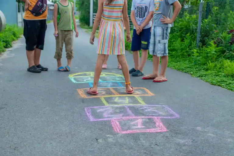 Kids playing hopscotch outdoors on a sunny day.