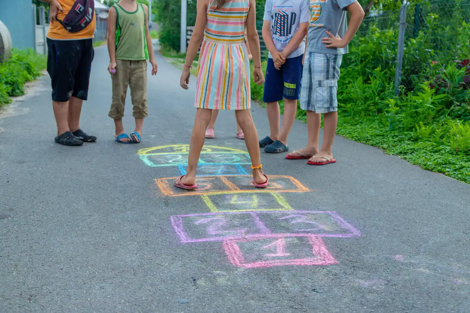 Kids playing hopscotch outdoors on a sunny day.