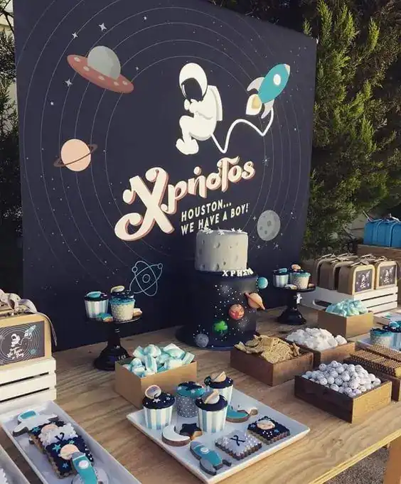 Space-themed birthday party decoration with astronaut, planets, and cake.
