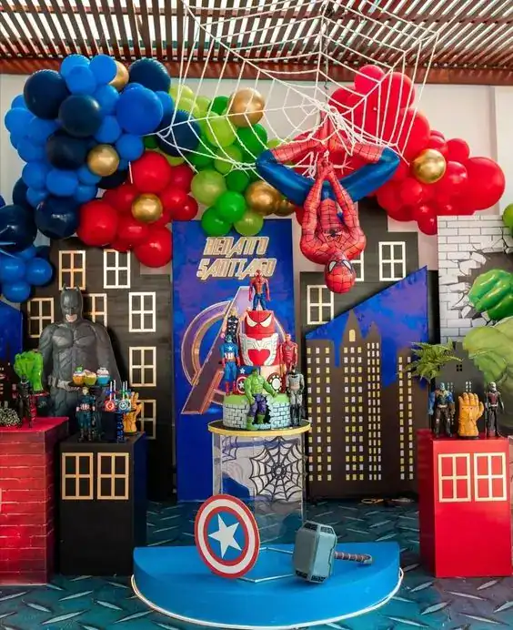 Spider-Man birthday party decor with balloons, cityscape backdrop, and superhero figures.