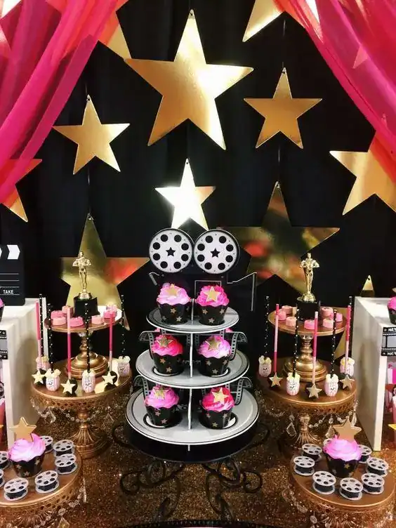 Star-themed birthday party backdrop with gold stars and pink cupcakes.
