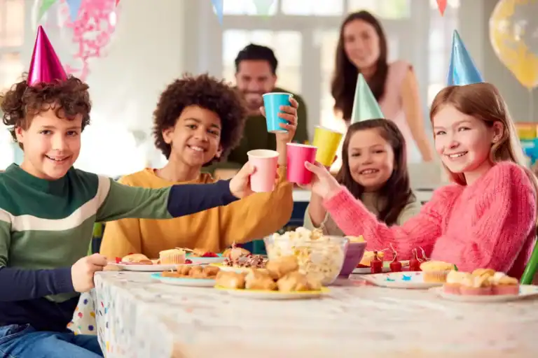 Happy teens celebrating birthday with party hats and snacks.