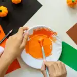 19 Thanksgiving Art Projects for Kids Kids painting pumpkin craft for Thanksgiving with orange paint and paper supplies.