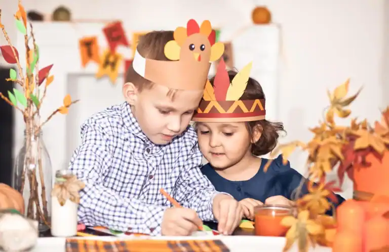 Kids making Thanksgiving craft with turkey headbands and autumn decorations.