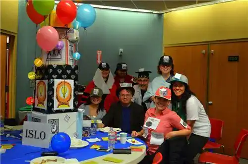 Group of teens celebrating with colorful balloons and themed hats at a party.